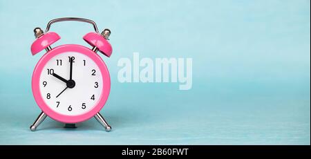 Save time, daylight saving concept, pink alarm clock on a blue background, web banner with copy space Stock Photo
