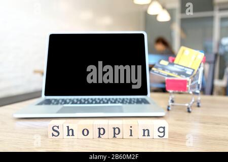 Computer laptop monitor notebook blank screen copy space for your text and Credit card in cart on wood table in a cafe or restaurant. Front wooden blo Stock Photo