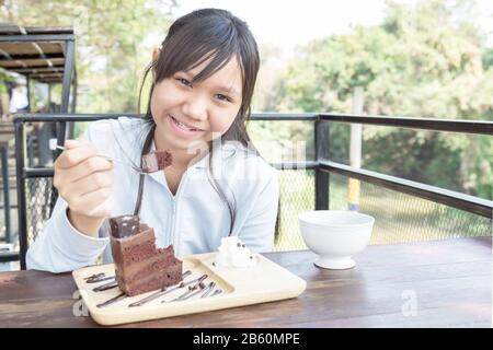 Asia teenage girl eating cake chocolate in restaurant or cafe. Stock Photo