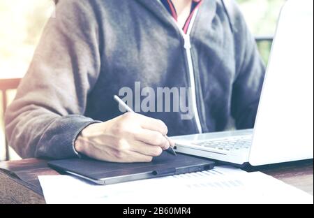 Asia middle age freelance working with mouse pen on laptop at outdoor restaurant or cafe. Stock Photo