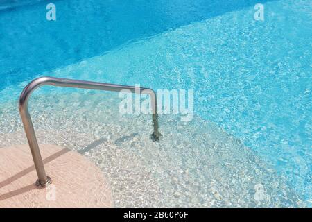 Calm swimming pool steps and handrail. In summer. Stock Photo