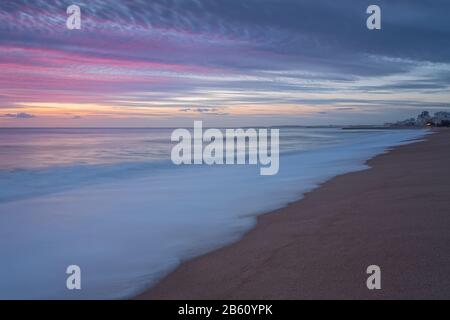 Pink sunset on the beach in Quarteira. Portugal for tourists. Stock Photo