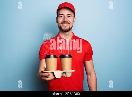 Courier is happy to deliver hot coffee. Cyan background Stock Photo