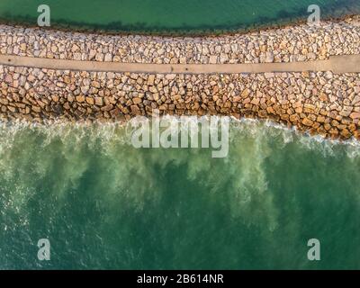 Aerial. Stone Industrial breakwater into the sea. Filmed from the sky. Portugal. Stock Photo
