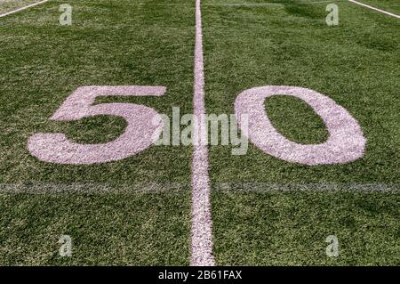 The fifty yard line marker on a football field with green artificial grass and white lines Stock Photo