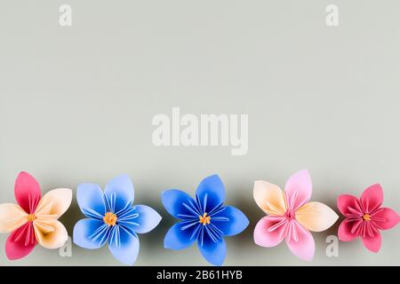 Colourful handmade paper flowers on light blue background with copyspace. design for greeting card. Creative layout border frame. Chic wedding invitat Stock Photo