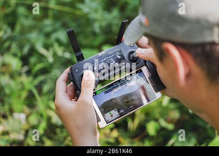 01 SEPTEMBER 2017, BASHKORTOSTAN, RUSSIA: closeup on male hands of drone operator with an amateur quadcopter remote control joystick, outdoors Stock Photo