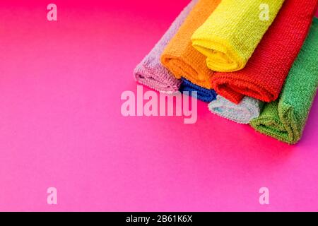 stacked colorful microfiber cleaning cloths on a pink background. Colorful, dry microfiber cloths for different surfaces cleaning in kitchen, bathroom Stock Photo
