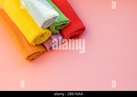 stacked colorful microfiber cleaning cloths on a pink background. Colorful, dry microfiber cloths for different surfaces cleaning in kitchen, bathroom Stock Photo