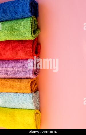 stacked colorful microfiber cleaning cloths on a pink background. Colorful, dry microfiber cloths for different surfaces cleaning in kitchen, bathroom Stock Photo