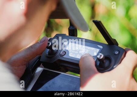 closeup on male hands of drone operator with an amateur quadcopter remote control joystick, outdoors Stock Photo