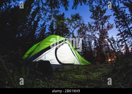 Tourist camp with a tent and a fire at night in the forest, shot on a fisheye lens Stock Photo