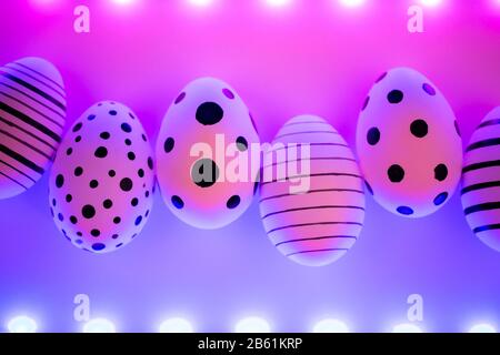Different graphic hand-painted eggs in Proton Purple neon light. Easter concept. Top view. Stock Photo