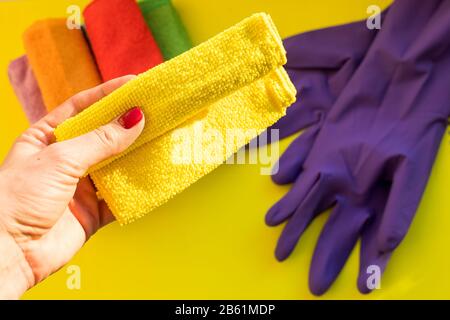 Female housekeeper holding a cleaning dry microfiber cloth.Cleaning or housekeeping concept background. purple rubber glove and Set of cleaning tools Stock Photo