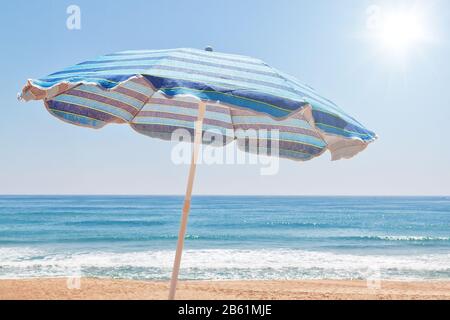 Blue for sun umbrella on the beach near the sea. Stock Photo