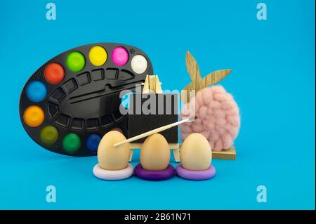 Colorful creative Easter still life with handicrafts featuring three eggs on purple rings, a natural fluffy cotton or wool rabbit and multicolored art Stock Photo