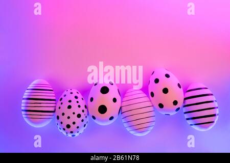 Different graphic hand-painted eggs in Proton Purple neon light. Easter concept. Top view. Stock Photo