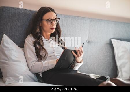 Businesswoman on business trip lying in hotel room and taking notes. Stock Photo