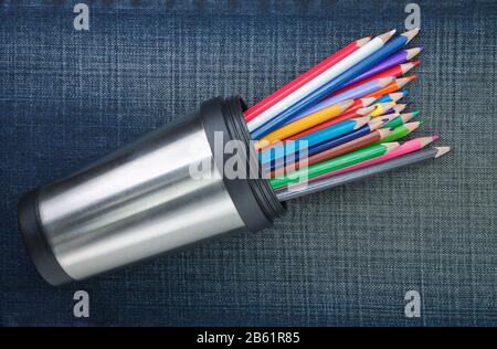 Group of colored pencils in cup with metal. On the jeans texture. Stock Photo