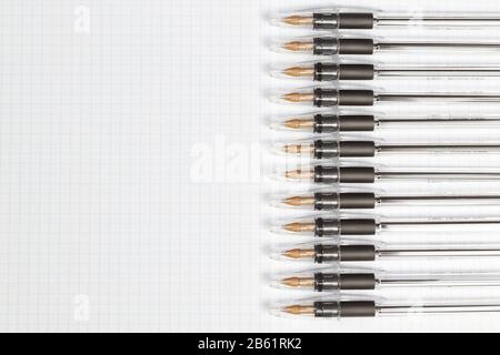Ball-point pens in a row on the paper in the cage. Place for note. Stock Photo