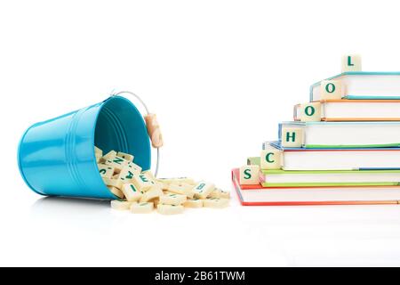 English letters spill out of the bucket and the word education on the books. Stock Photo