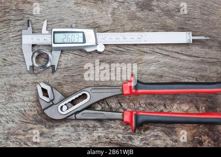 Caliper and adjustable wrench with a detail on a wooden texture. Close-up. Stock Photo