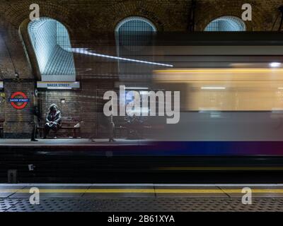 London, England, UK - March 3, 2020: Commuters wait on the platforms of London Underground's histoic Baker Street station as a Hammersmith & City Line Stock Photo