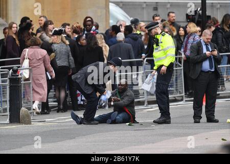 Police officers detain one of two men who ran into the road outside Westminster Abbey, London, ahead of the Commonwealth Service. Stock Photo