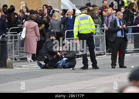 Police officers detain one of two men who ran into the road outside Westminster Abbey, London, ahead of the Commonwealth Service. Stock Photo