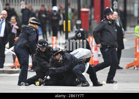 Police officers detain one of two men who ran into the road outside Westminster Abbey, London, ahead of the Commonwealth Service. Stock Photo