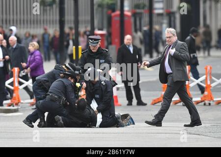 Police officers detain one of two men who ran into the road outside Westminster Abbey, London, ahead of the Commonwealth Service. Stock Photo