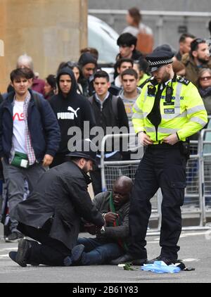 Police officers detain one of two men who ran into the road outside Westminster Abbey, London, ahead of the Commonwealth Service. Stock Photo