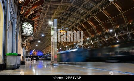 London, England, UK - February 25, 2020: A Great Western Railway train departs London under the great Victorian arch roof of Paddington Station at nig Stock Photo