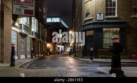London, England, UK - February 25, 2020: Low rise houses, pubs and offices stand on Cloth Fair and Kinghorn Street in the Smithfield area of the City Stock Photo