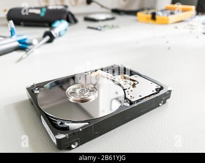 Opened computer hard drive on a table prepared to be fixed. Stock Photo