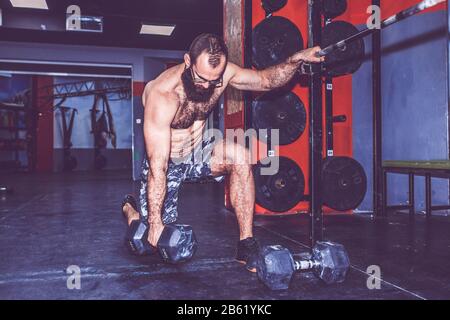 Young bearded man doing weight lifting in gym Stock Photo