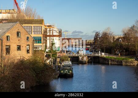 London, England, UK - January 9, 2020: Narrowboats are moored in the River Lea Navigation at Old Ford Locks, beside the regenerating Fish Island and O Stock Photo