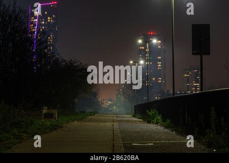 Mist shrounds tower blocks and high rise apartment buildings along the Greenway in Stratford, east London, at night. Stock Photo