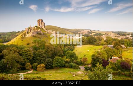 Evening sun shines on the ruined walls of the mediaeval castle at Corfe Castle in Dorset's Purbeck Hills. Stock Photo