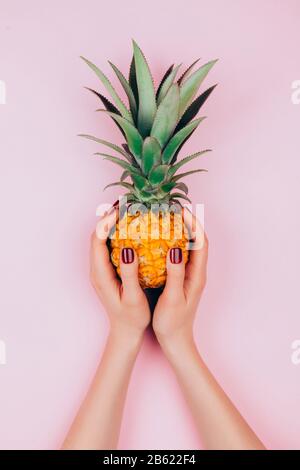 Hands with pineapple on stylish pink background. Stock Photo