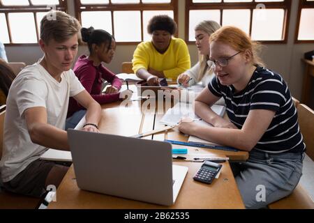 Front view of students working on group with a laptop Stock Photo