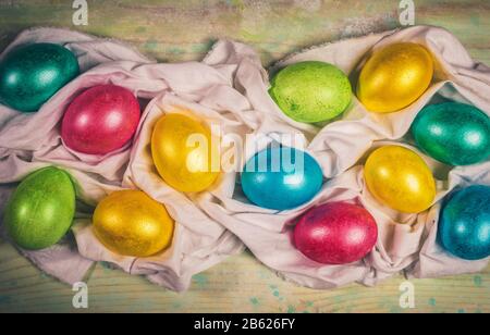 Creative Easter festive layout  with multicolored Easter eggs laid out on white textile napkin with pleats. Holiday decor. Warm toning. Retro toned im Stock Photo