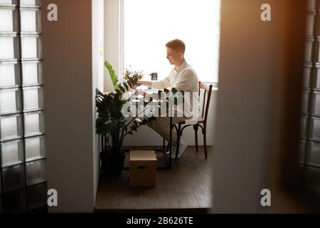 handsome cheerful young man working and typing on laptop at home, full length side view photo.guy playing computer games Stock Photo
