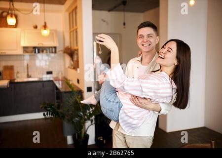 funny young family rejoicing at buying a house, flat , apartment, family laughing , having fun in a new house, celebration, Stock Photo