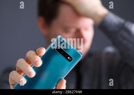 Pensive man holding an hand broken expensive modern smartphone Stock Photo