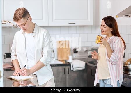 clever guy concentrated on creating a business project while his girlfriend giving advice to him, recommending something to develop business Stock Photo