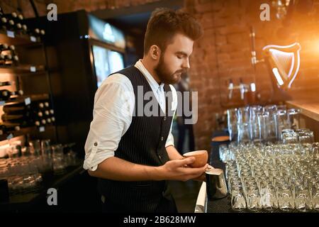 young man creating pleasant taste of coffee, art , creativity concept , duty , close up side view photo, small business Stock Photo