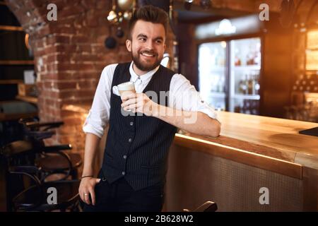 young happy bearded waiter laughing, looking up, holding smoothie, close up side view photo.awesome flavor Stock Photo