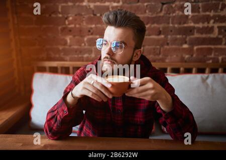 serious man is having a rest at the cafe with loft interior. close up photo. buisnessman solving problems, making up a plan, idea, project, looking fo Stock Photo