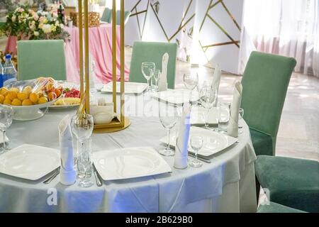 The table in the restaurant is served for dinner. On a table with a white tablecloth, empty wine glasses, a plates, napkins. Selective focus Stock Photo